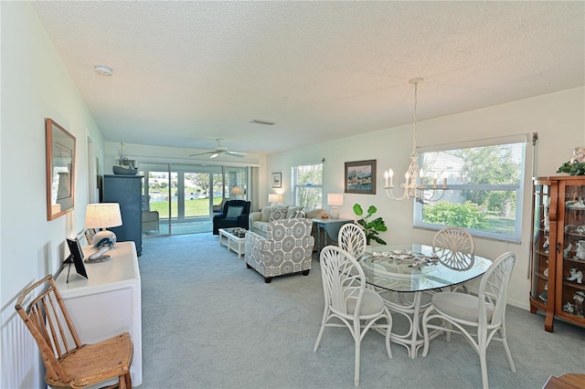 dining room with light carpet, ceiling fan with notable chandelier, and a textured ceiling