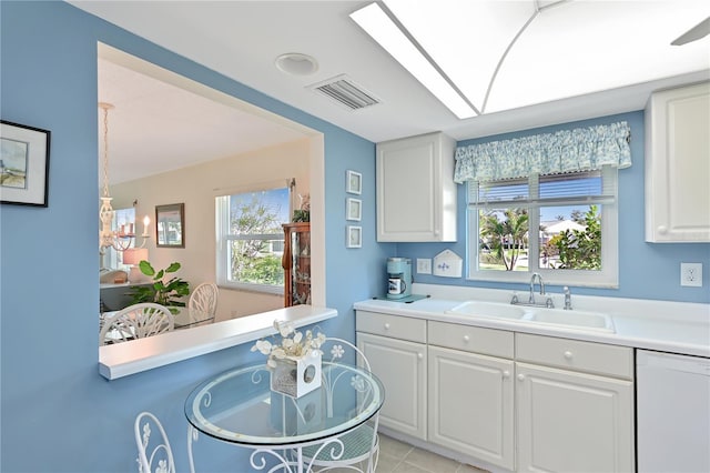 kitchen with visible vents, a sink, white cabinets, light countertops, and dishwasher