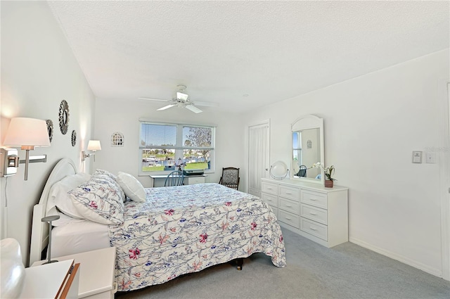 bedroom with baseboards, light carpet, a textured ceiling, and a ceiling fan