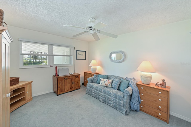 living area with baseboards, a ceiling fan, carpet flooring, and a textured ceiling