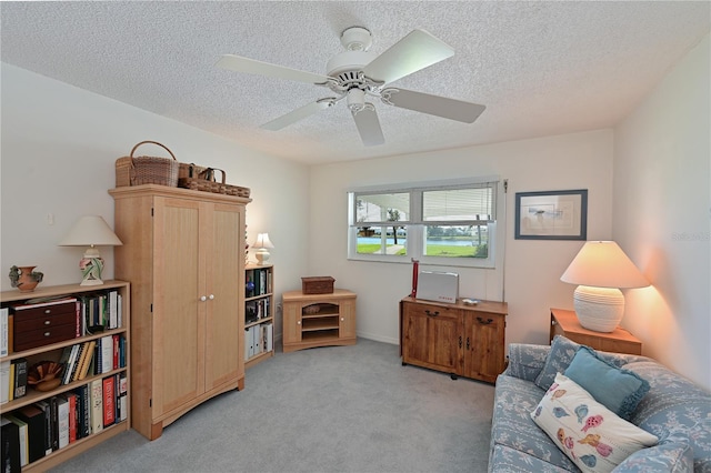 living area with light colored carpet, a ceiling fan, and a textured ceiling