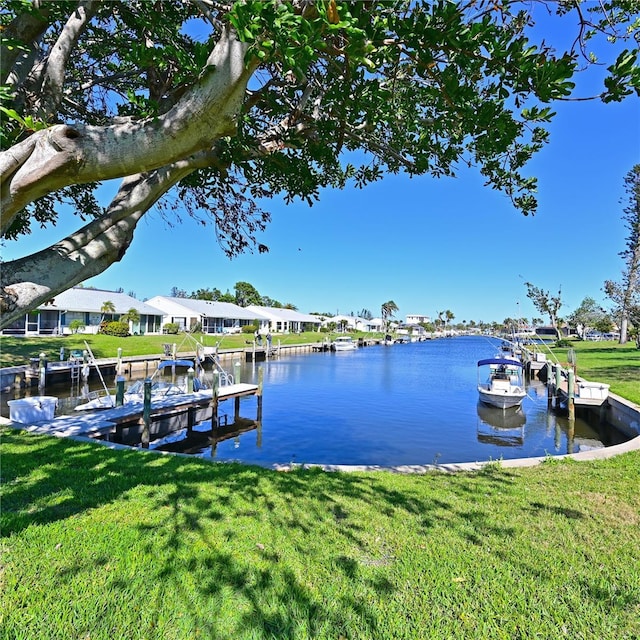 view of dock with a yard and a water view