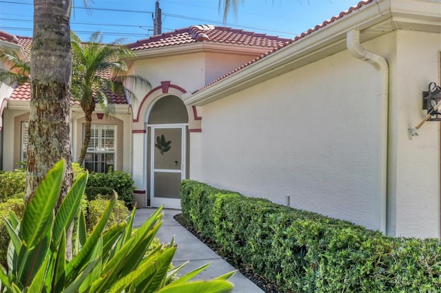 property entrance with stucco siding and a tiled roof