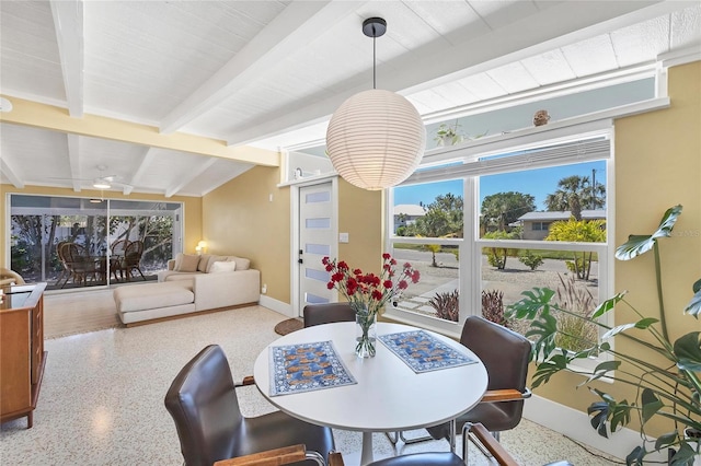 dining area featuring lofted ceiling with beams, baseboards, and speckled floor