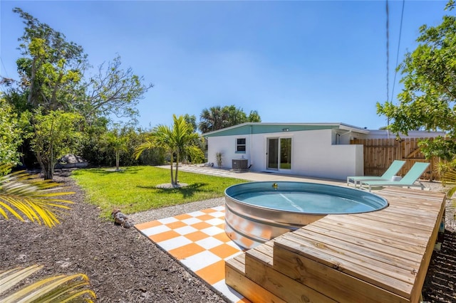 rear view of house with a patio, fence, stucco siding, central air condition unit, and a lawn