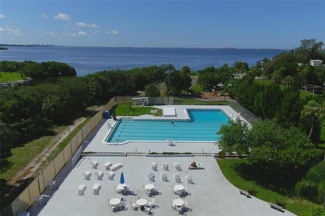 pool featuring a patio area, a water view, and fence