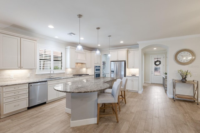 kitchen featuring visible vents, arched walkways, a sink, appliances with stainless steel finishes, and a kitchen bar