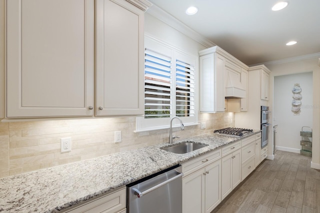 kitchen with ornamental molding, a sink, tasteful backsplash, stainless steel appliances, and light wood-style floors