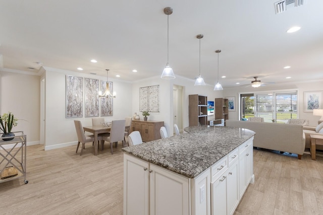 kitchen with light wood-style floors, a center island, and crown molding