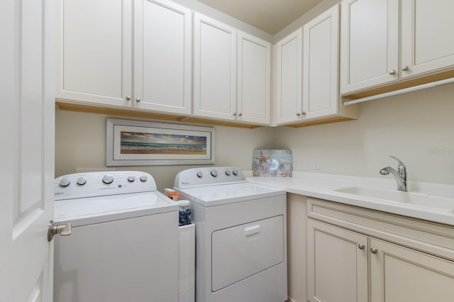 clothes washing area featuring cabinet space, washer and dryer, and a sink