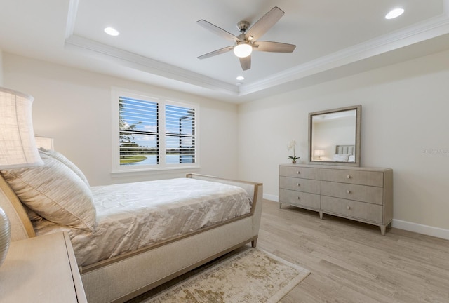 bedroom featuring a raised ceiling, light wood-style floors, and ornamental molding