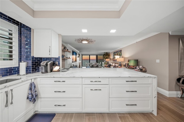 kitchen with white cabinetry, crown molding, and light stone counters