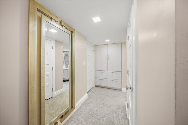 hall with light colored carpet and baseboards