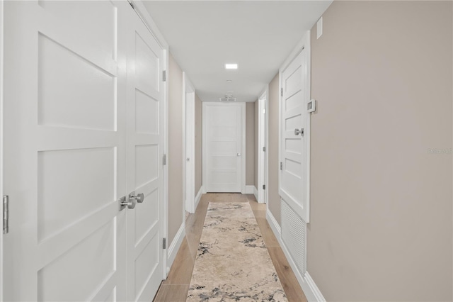 hallway with light wood-style flooring and baseboards