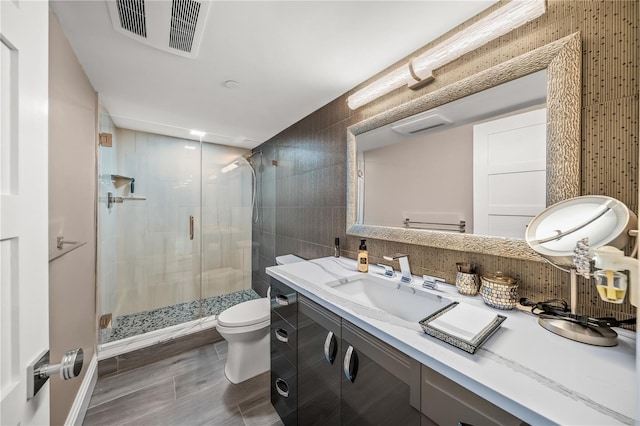 full bathroom with vanity, visible vents, a stall shower, tile walls, and toilet