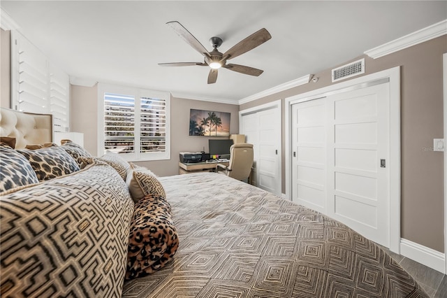 bedroom featuring ceiling fan, visible vents, two closets, and ornamental molding