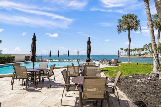 view of patio with outdoor dining space, a water view, and a community pool