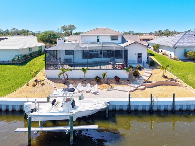 back of property featuring a lanai, boat lift, a lawn, and a water view