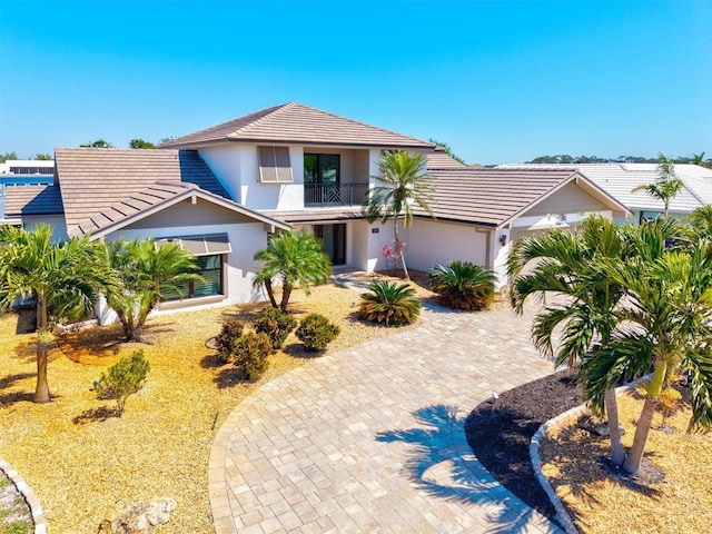 view of front of house featuring stucco siding, a tiled roof, decorative driveway, and a balcony