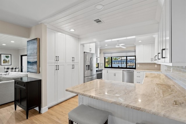 kitchen with visible vents, backsplash, appliances with stainless steel finishes, a peninsula, and white cabinets