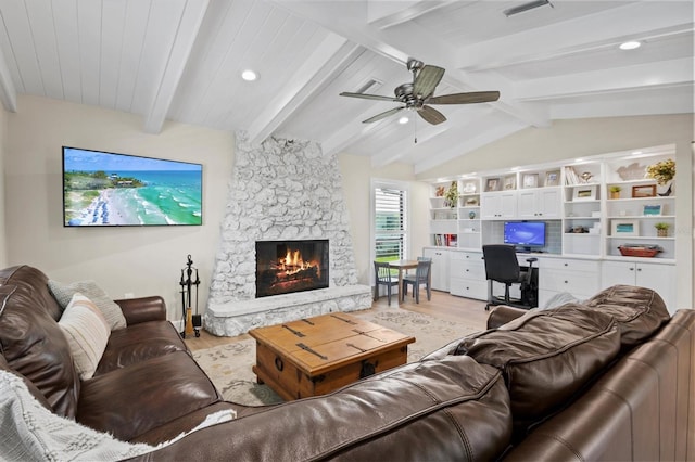 living area with visible vents, vaulted ceiling with beams, light wood-type flooring, a fireplace, and a ceiling fan