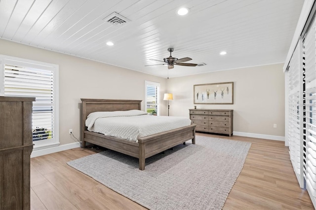 bedroom with baseboards, multiple windows, and light wood-style flooring