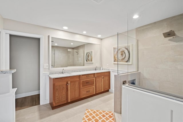 bathroom with double vanity, recessed lighting, a walk in shower, and a sink