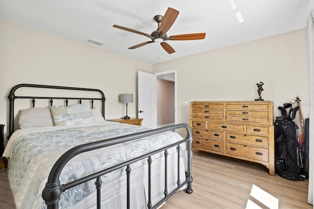 bedroom featuring light wood finished floors, visible vents, and a ceiling fan