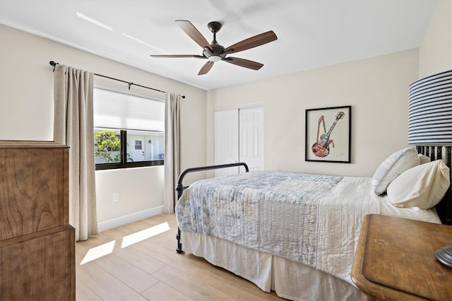 bedroom featuring light wood-style floors, baseboards, a closet, and ceiling fan