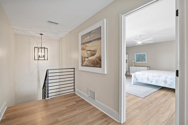 hallway featuring wood finished floors, an upstairs landing, and visible vents