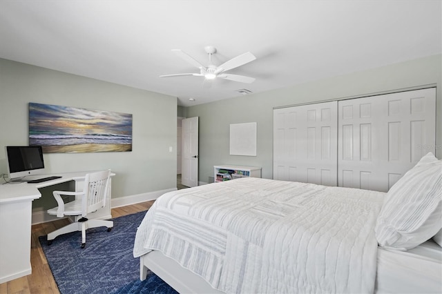 bedroom with visible vents, ceiling fan, baseboards, wood finished floors, and a closet