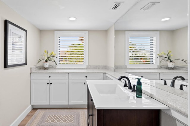 kitchen featuring visible vents, white cabinets, light countertops, and a sink