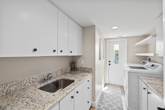 laundry area with visible vents, baseboards, cabinet space, a sink, and washing machine and dryer