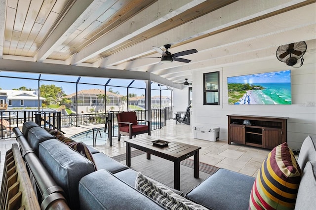 living room with beam ceiling, stone tile floors, and a ceiling fan