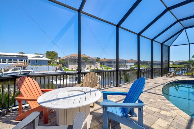 view of patio / terrace featuring glass enclosure, a water view, and a residential view