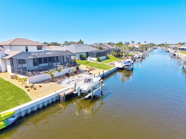 dock area with glass enclosure, a water view, and boat lift