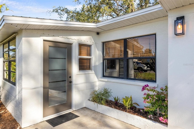 view of exterior entry with visible vents and stucco siding