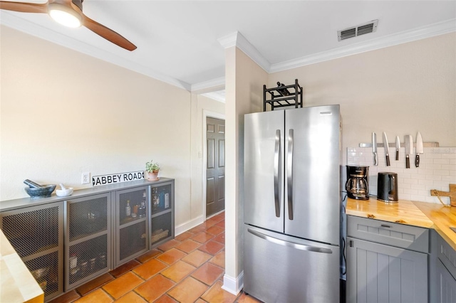 kitchen with visible vents, crown molding, decorative backsplash, gray cabinets, and freestanding refrigerator