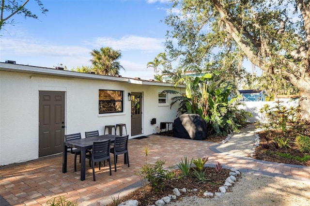 rear view of house featuring outdoor dining space, stucco siding, and a patio