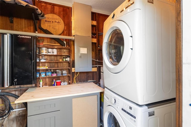 washroom featuring laundry area, electric panel, stacked washer / drying machine, and a textured ceiling