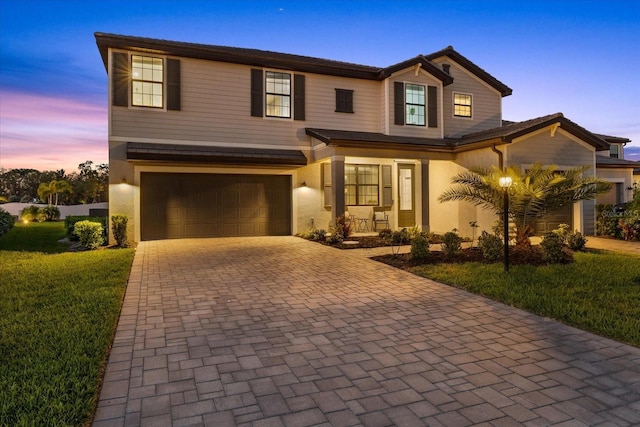 view of front facade with a front yard, decorative driveway, covered porch, and an attached garage