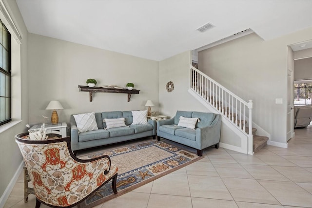 living room with light tile patterned floors, visible vents, stairs, and baseboards