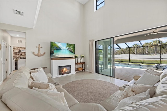 living area featuring a glass covered fireplace, visible vents, light tile patterned flooring, and a sunroom