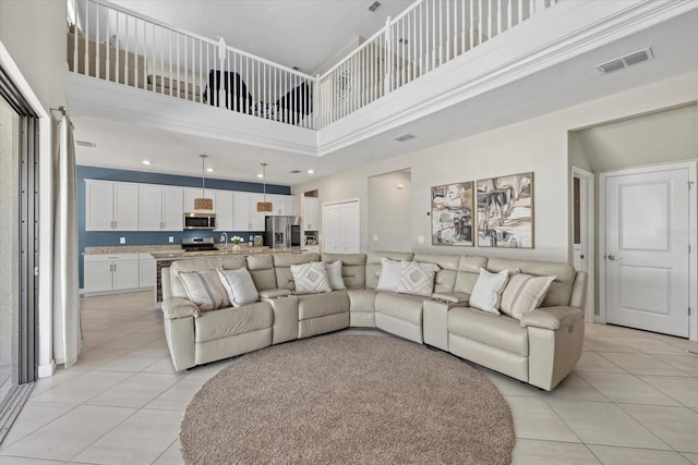 living room featuring visible vents, light tile patterned flooring, and a towering ceiling