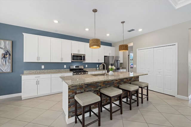 kitchen featuring a sink, stainless steel appliances, an island with sink, and white cabinets