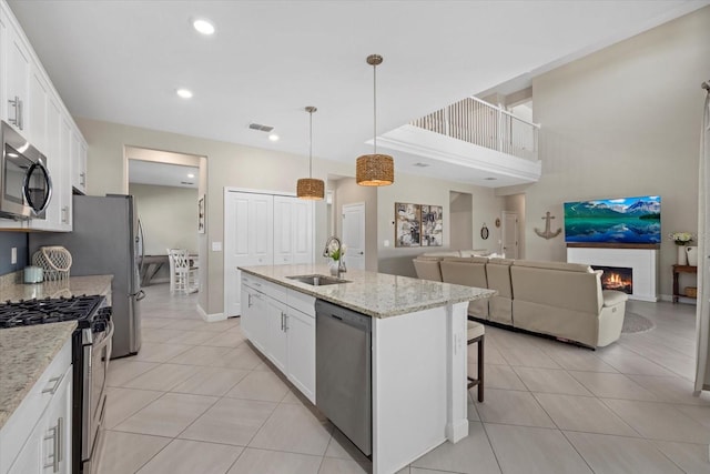 kitchen featuring a sink, appliances with stainless steel finishes, light tile patterned flooring, and white cabinets