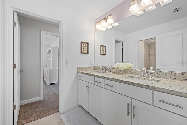 bathroom with double vanity, baseboards, a tile shower, and a sink