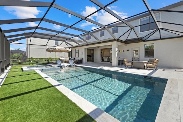 pool featuring a yard, glass enclosure, an in ground hot tub, ceiling fan, and a patio area