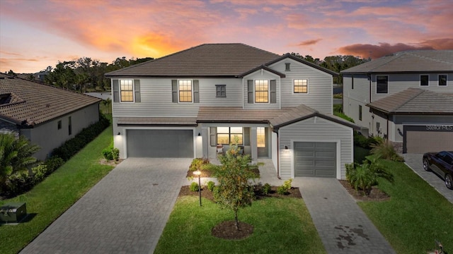 view of front of property with a yard, decorative driveway, an attached garage, and a tiled roof