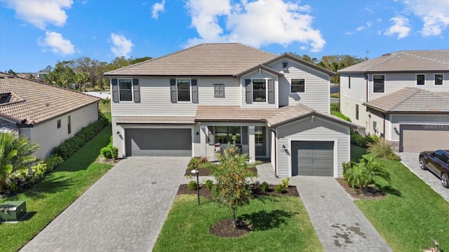 view of front of property featuring a tile roof, decorative driveway, and a front yard